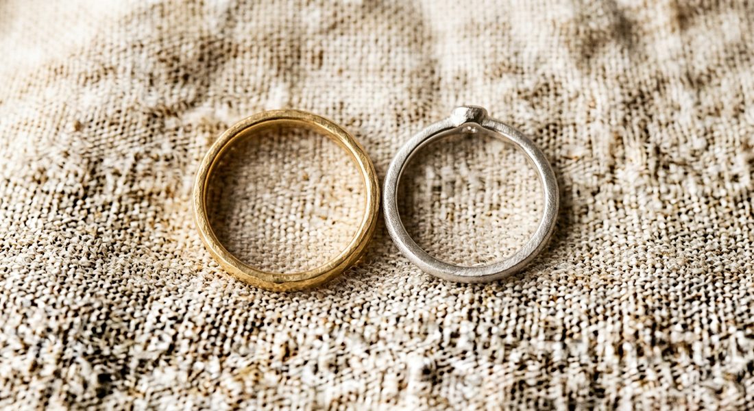 A pair of handcrafted wedding rings with a diamond on cream linen